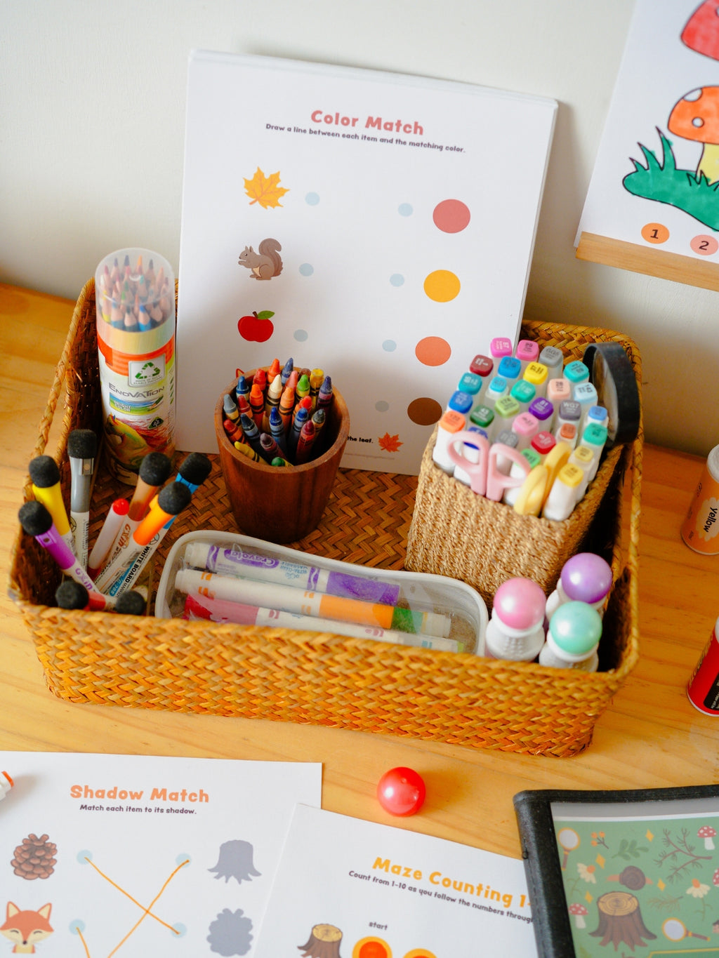 Colorful stationery items including markers, crayons, and a book on a wooden surface.
