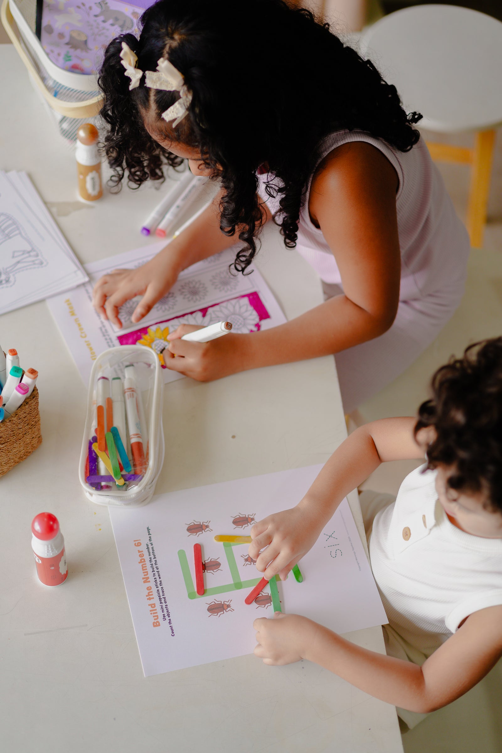 Two children engaged in a coloring activity at a table with crayons and markers.
