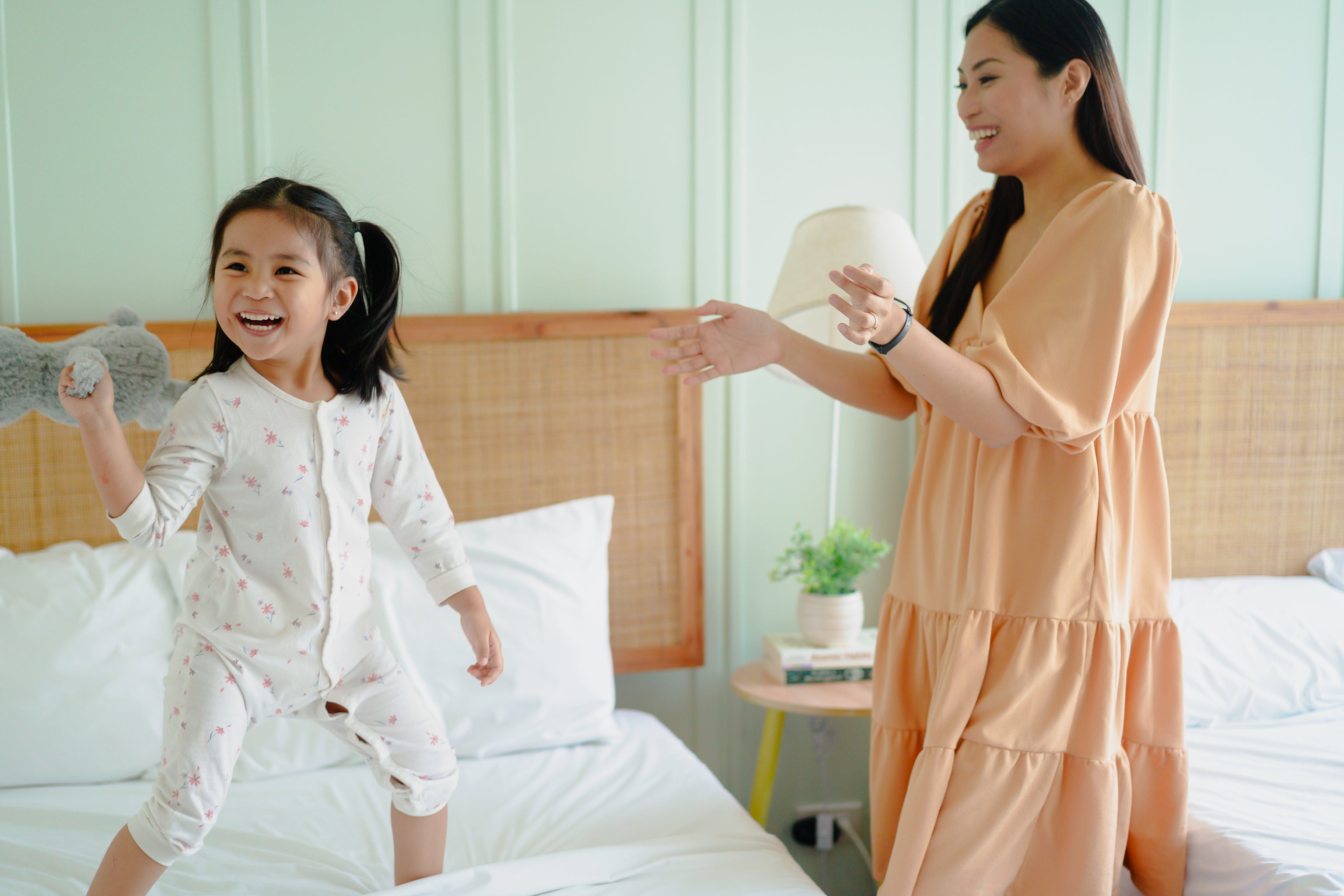 Woman and child in pajamas on a bed in a bedroom setting