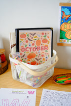 October activity pages for kids on a table with craft supplies, in a white basket with a wooden handle.